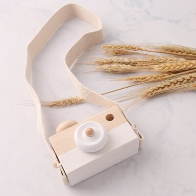 Wooden baby camera white over a marble background and 9 wheat ears placed decoratively to the right.