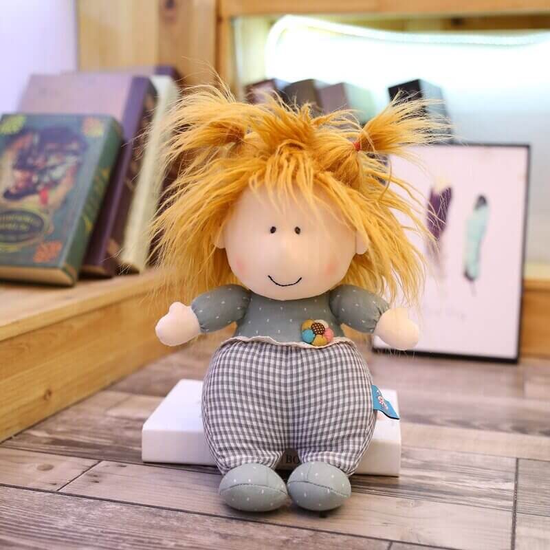 Playful doll in blue with messy hair sitting on a book