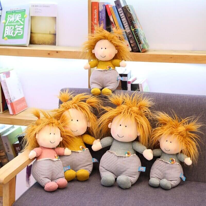 Five playful dolls in pink, blue, and yellow with messy hair sitting on a couch together.