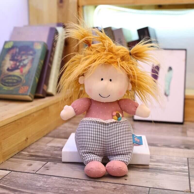 Playful doll in pink with messy hair sitting on a book